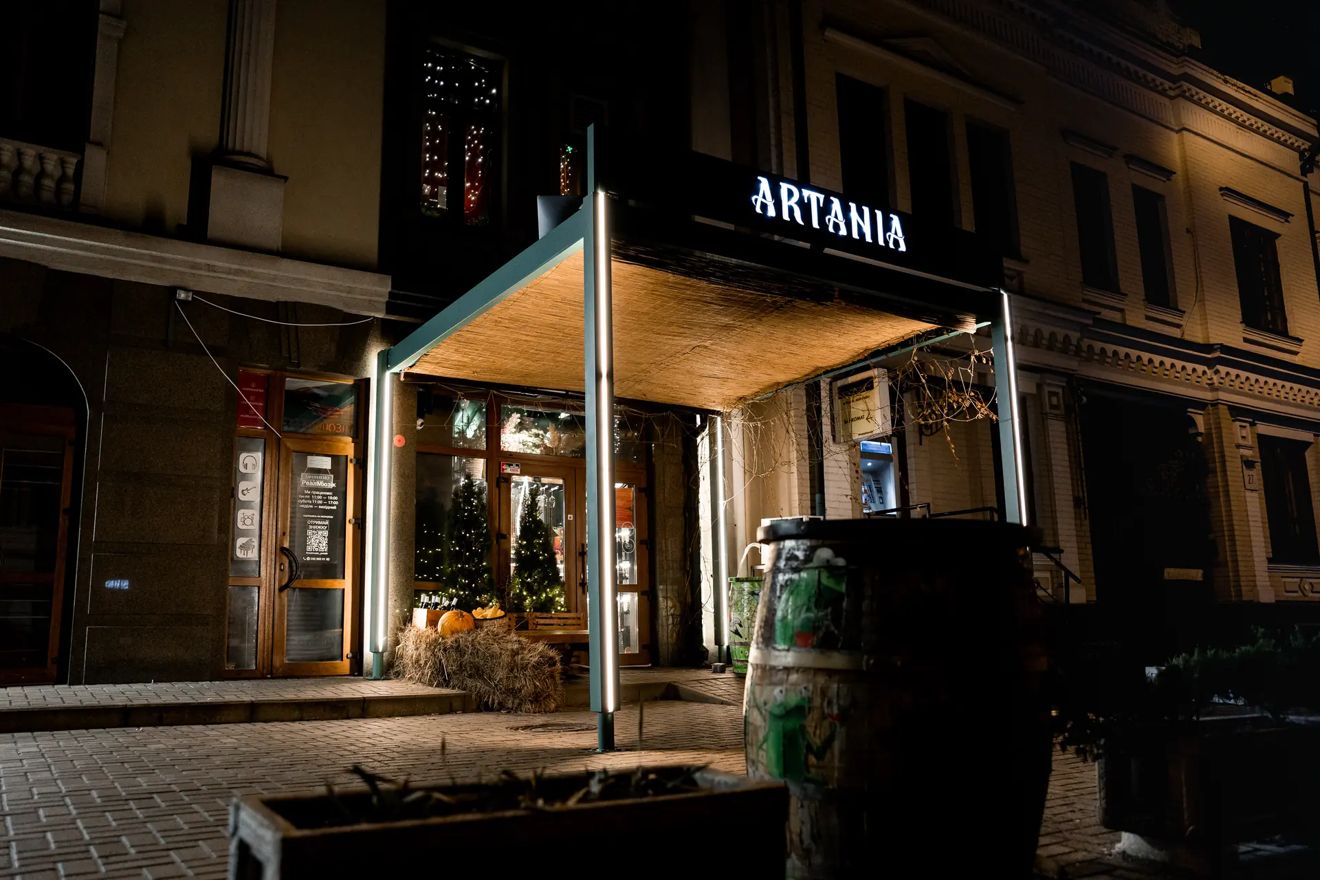 Фасад бару Artania вночі з підсвіченою вивіскою на Хориві, Київ